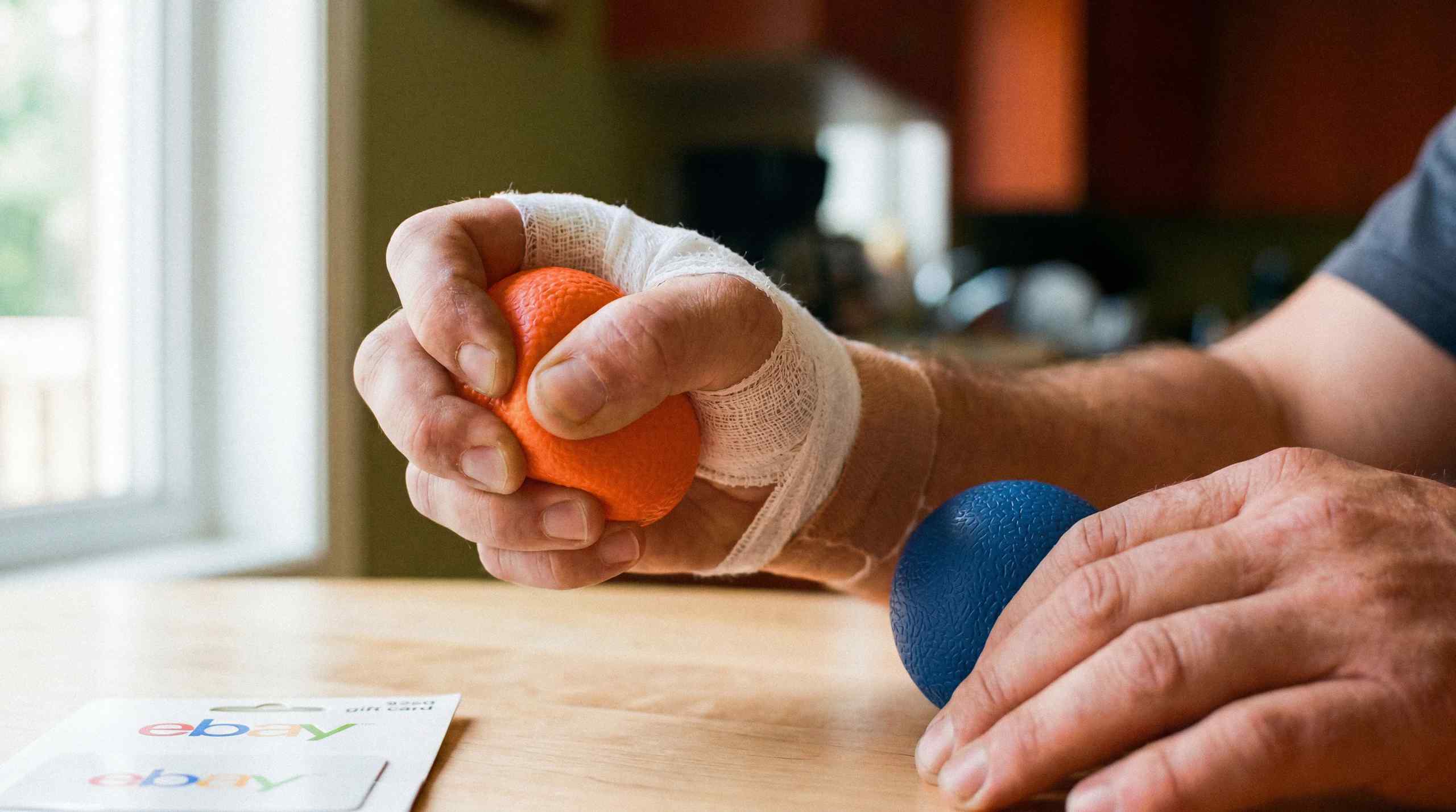 A bandaged wrist going through rehab by squeezing a ball.